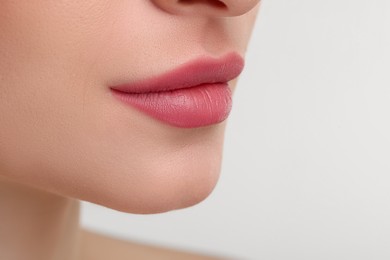 Photo of Young woman with beautiful full lips on white background, closeup