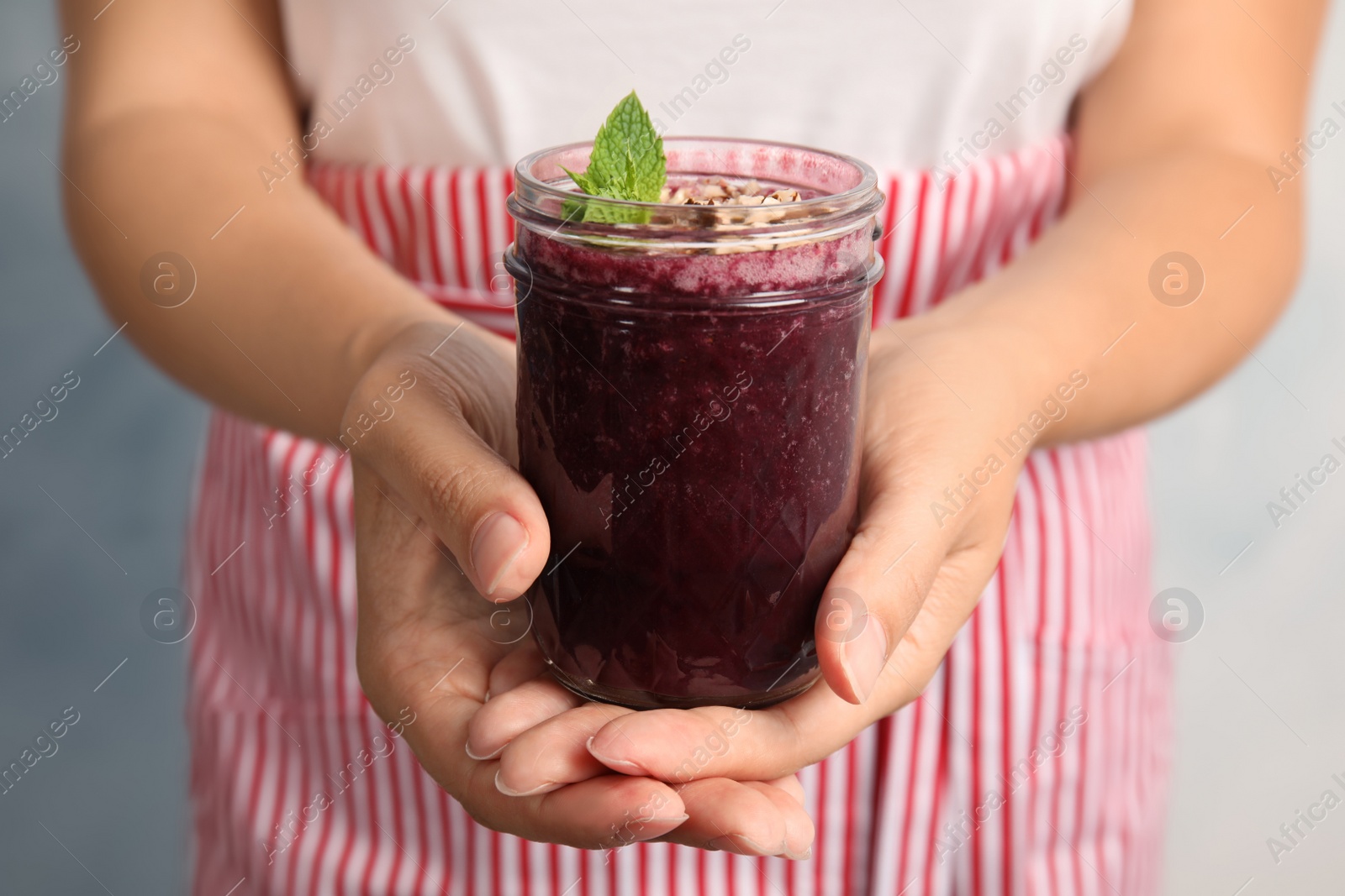 Photo of Woman holding mason jar of delicious acai juice, closeup