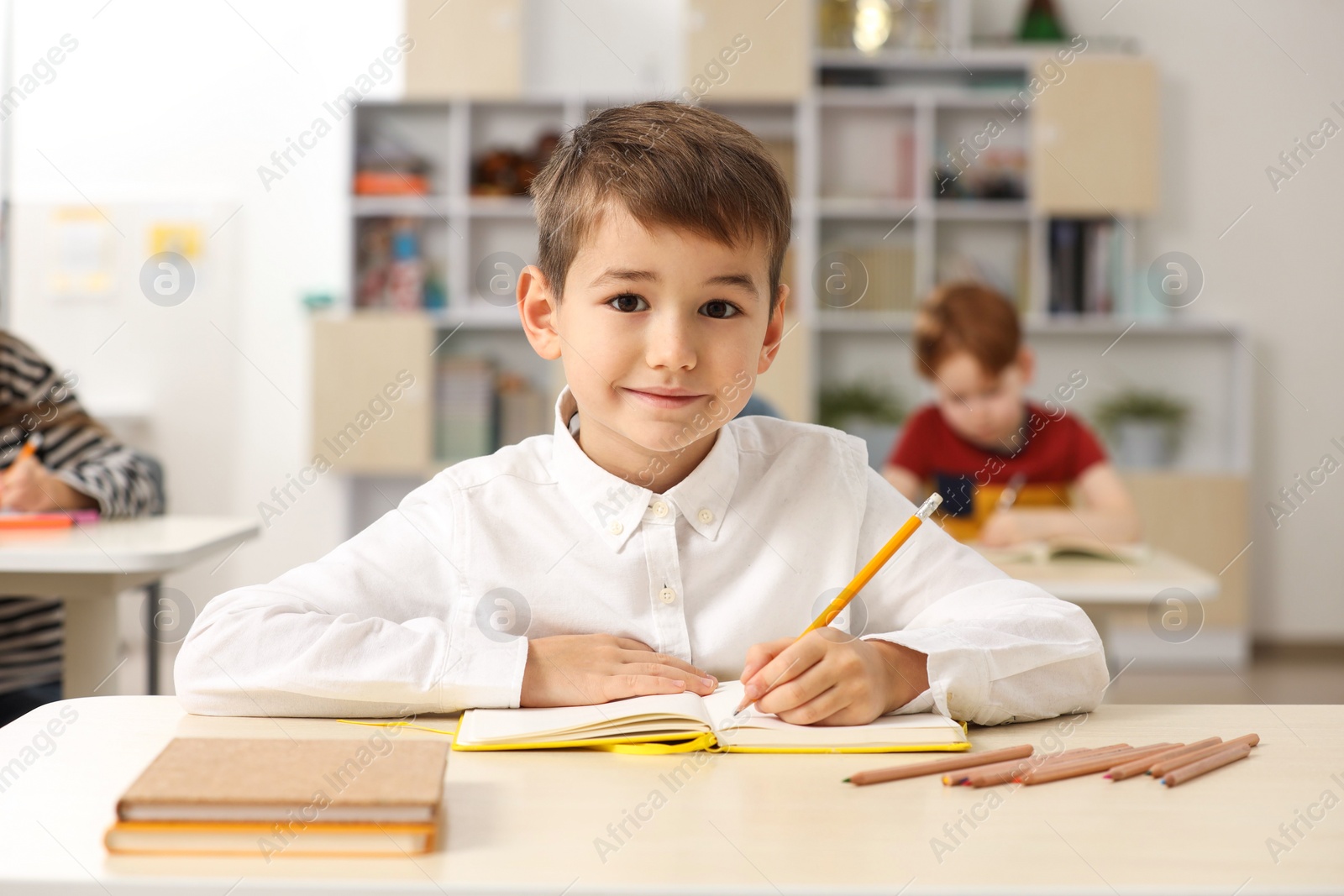 Photo of Portrait of cute little boy studying in classroom at school