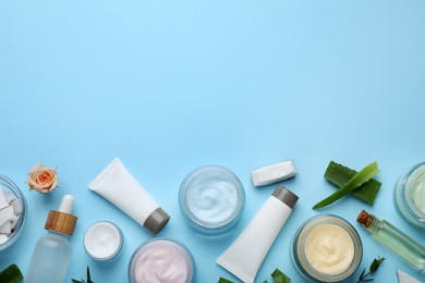 Photo of Body cream and other cosmetics with ingredients on light blue background, flat lay. Space for text