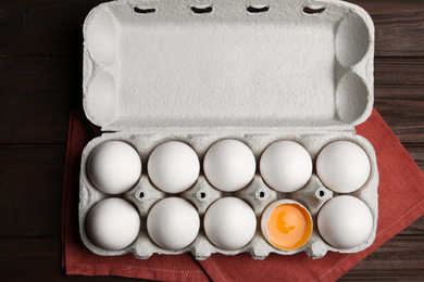 Photo of Fresh raw chicken eggs in box on wooden table, flat lay