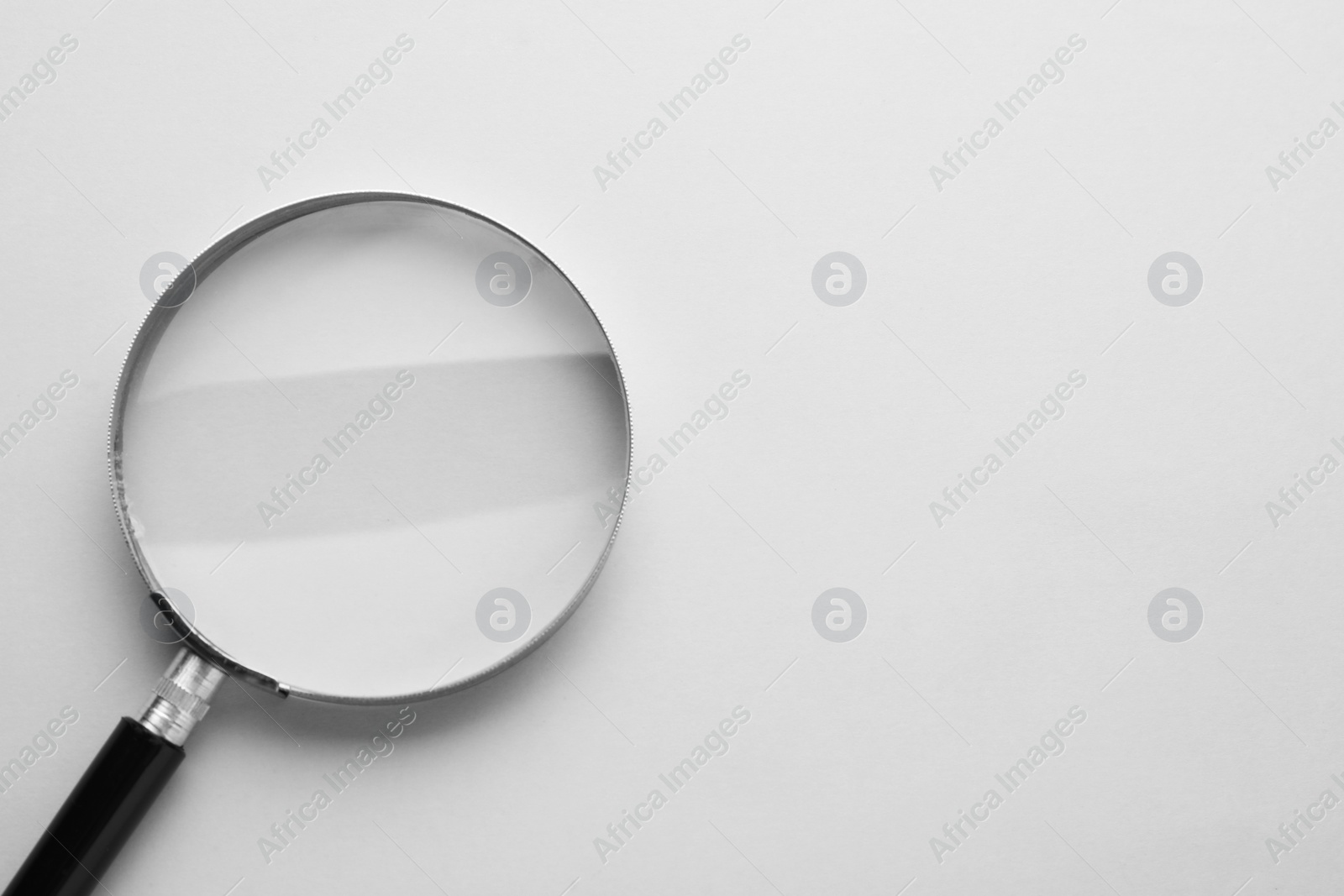 Photo of Magnifying glass on light grey background, top view. Space for text