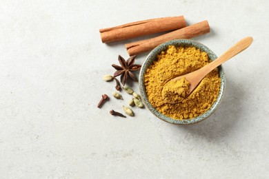 Photo of Dry curry powder in bowl and other condiments on light table, flat lay. Space for text