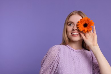 Photo of Beautiful woman with spring flower in hand on purple background, space for text