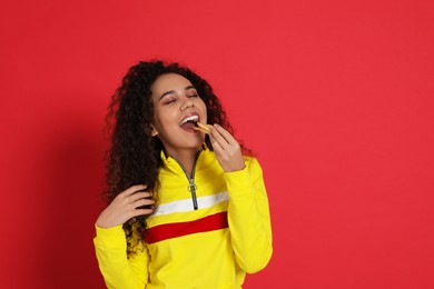 Photo of African American woman eating French fries on red background, space for text