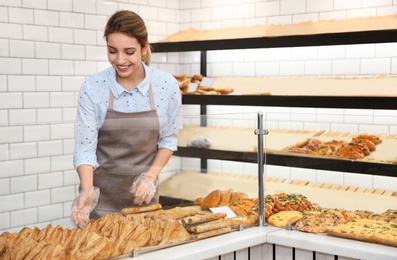 Photo of Beautiful woman near showcase with pastries in bakery shop