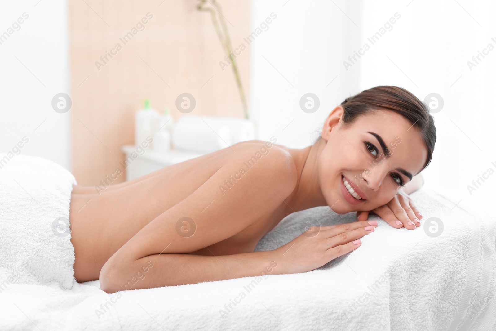 Photo of Beautiful young woman relaxing on massage table in spa salon