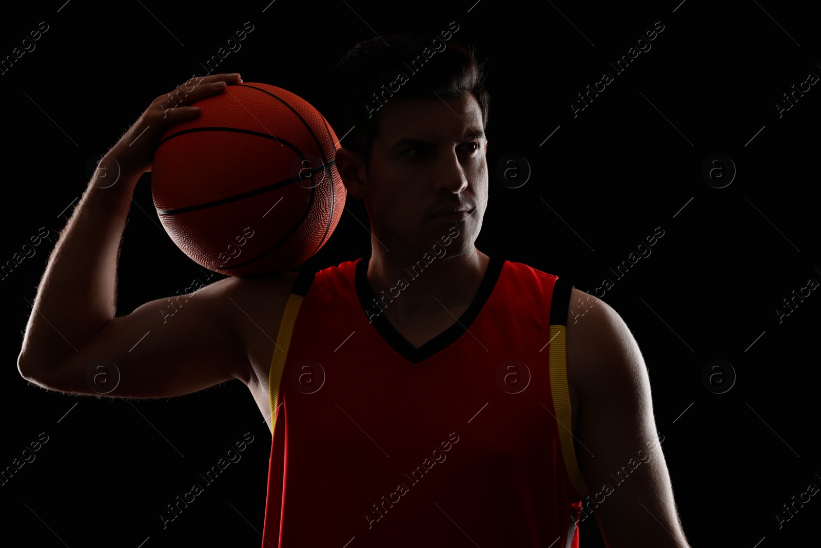 Photo of Basketball player with ball on black background