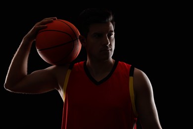 Basketball player with ball on black background