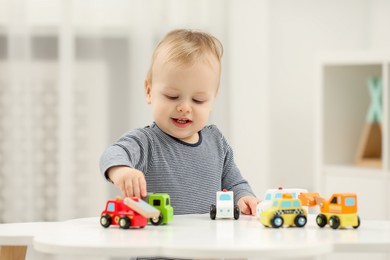 Photo of Children toys. Cute little boy playing with toy cars at white table in room