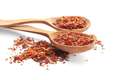 Wooden spoons and chili pepper flakes on white background