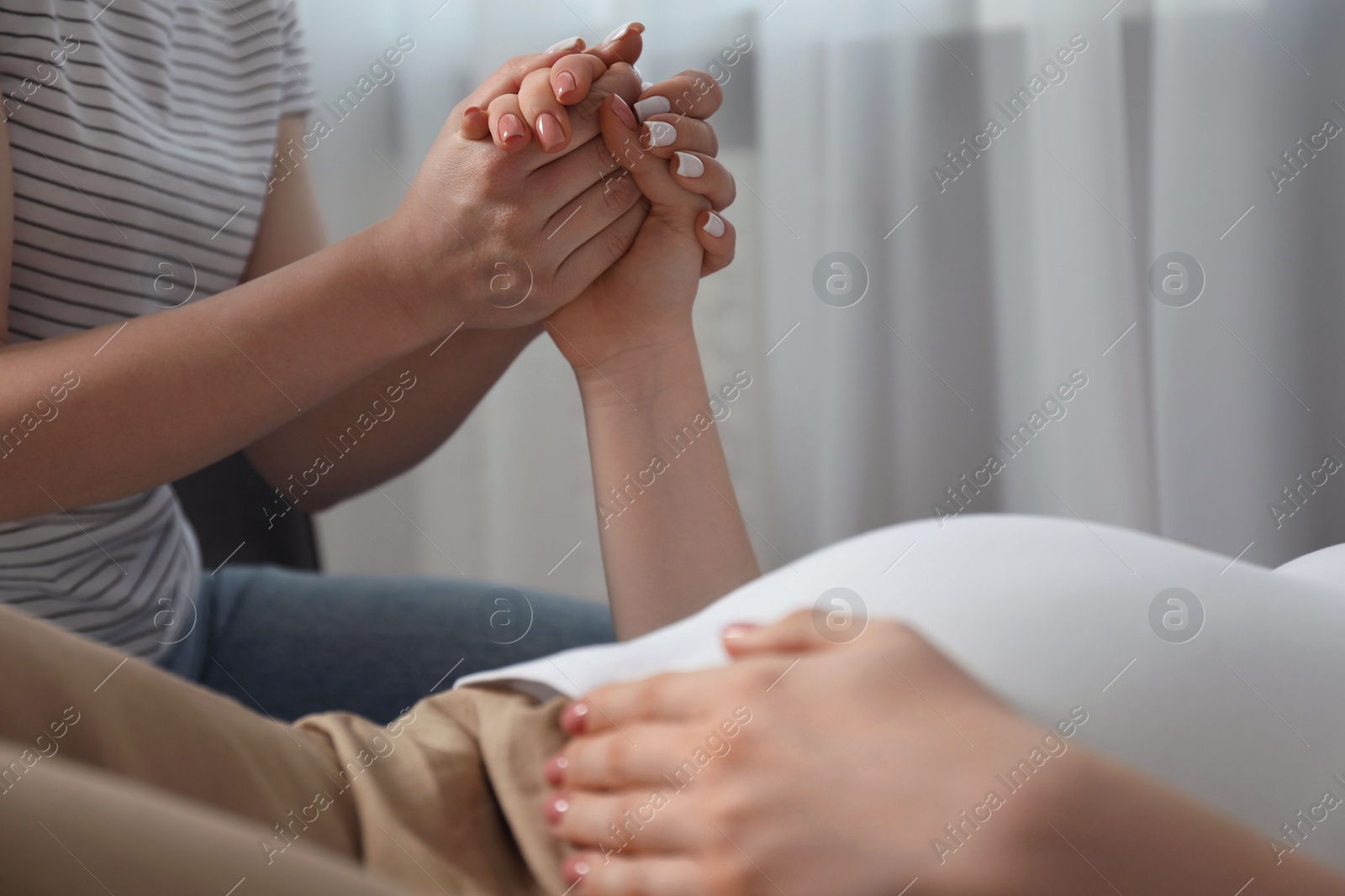 Photo of Doula taking care of pregnant woman indoors, closeup. Preparation for child birth