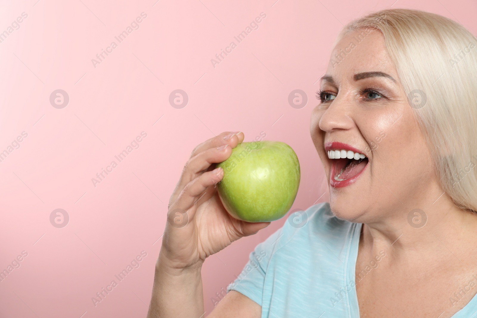 Photo of Smiling woman with perfect teeth and green apple on color background. Space for text