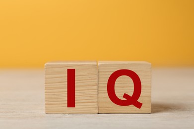 Photo of Wooden cubes with abbreviation IQ on table. Space for text