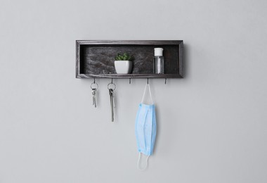 Photo of Wooden hanger for keys with different stuff on light grey wall