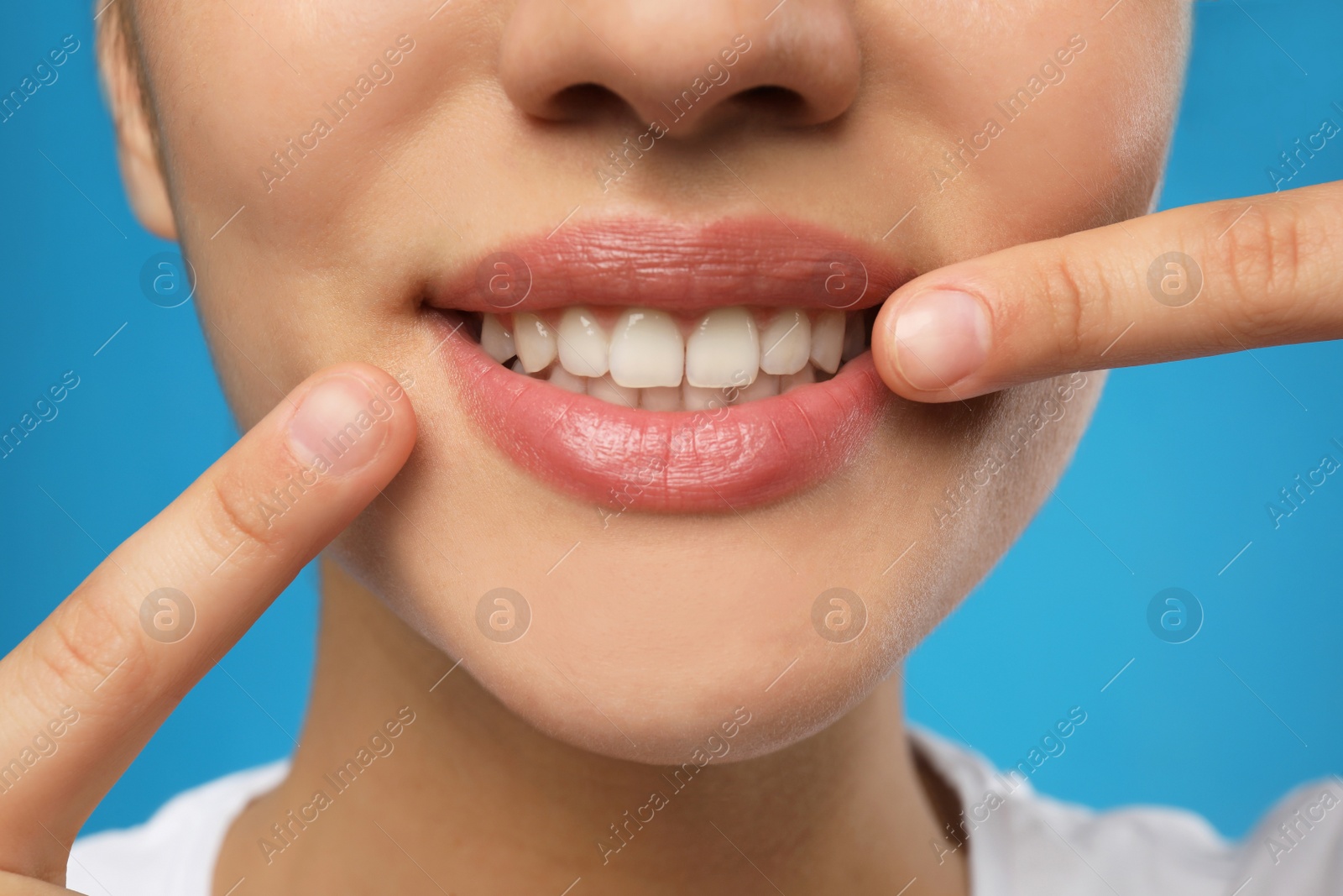 Photo of Woman with healthy teeth and beautiful smile on blue background, closeup. Cosmetic dentistry