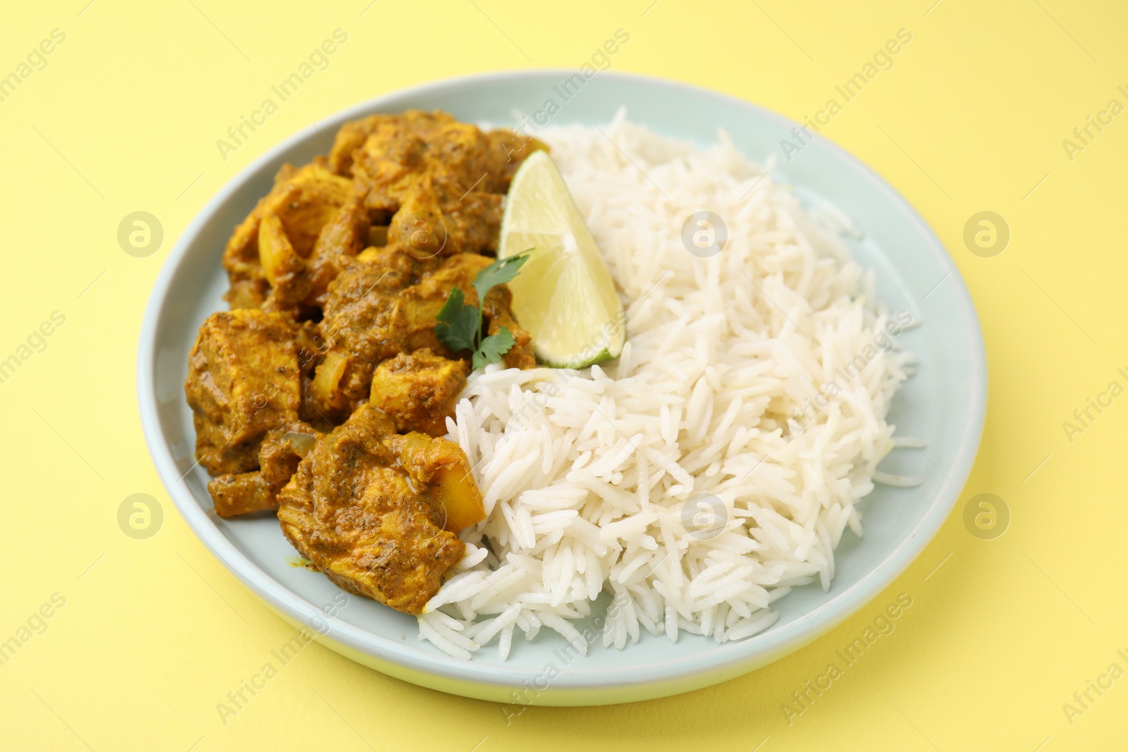 Photo of Delicious chicken curry with rice on yellow background, closeup