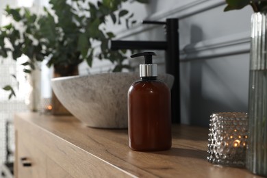 Photo of Soap bottle near vessel sink on bathroom vanity. Interior design