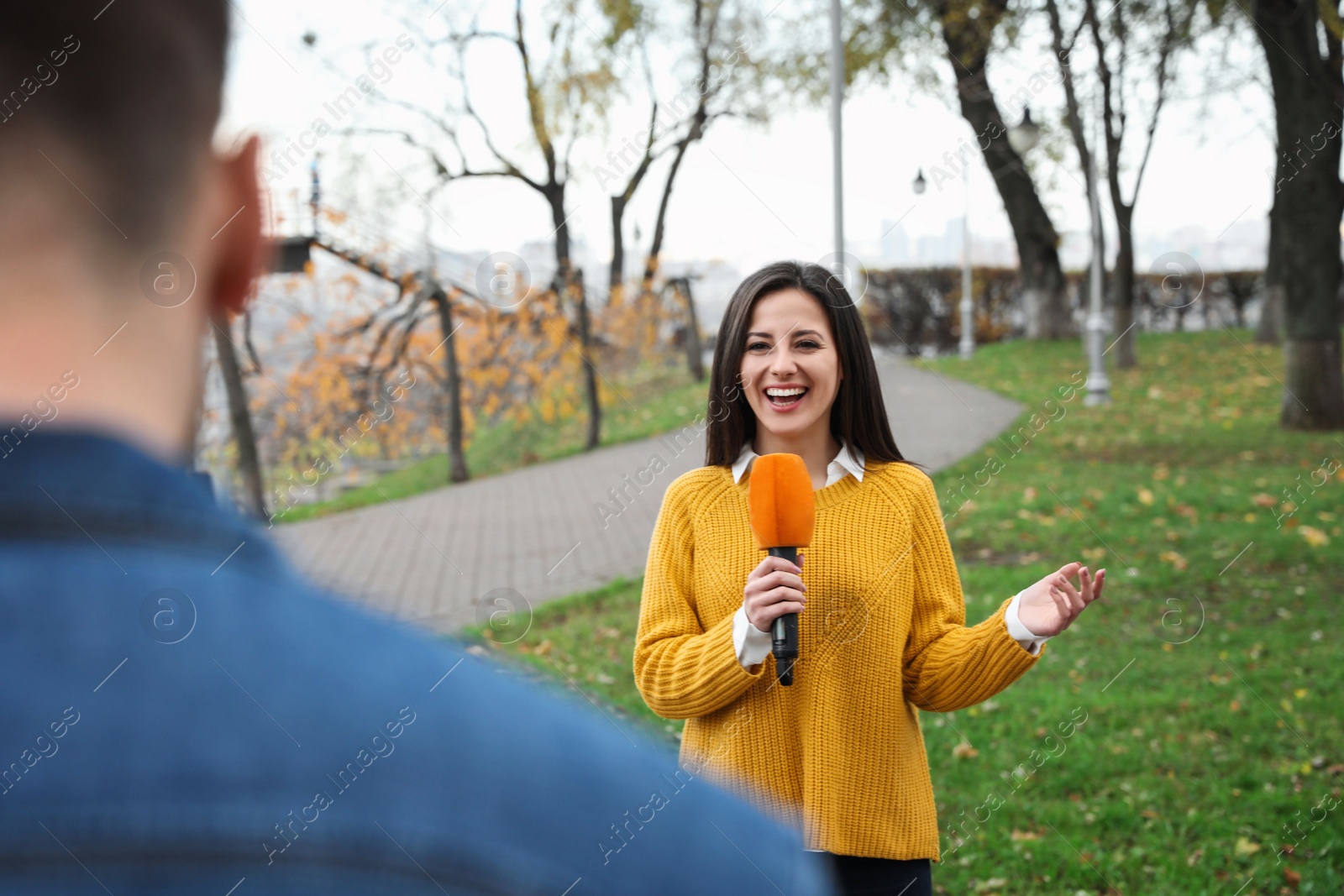 Photo of Young journalist and video operator working in park