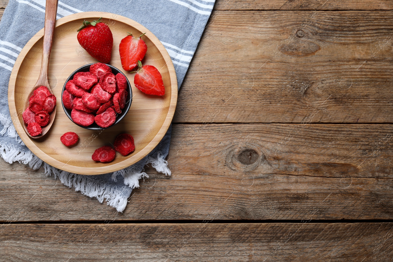 Photo of Freeze dried and fresh strawberries on wooden table, top view. Space for text