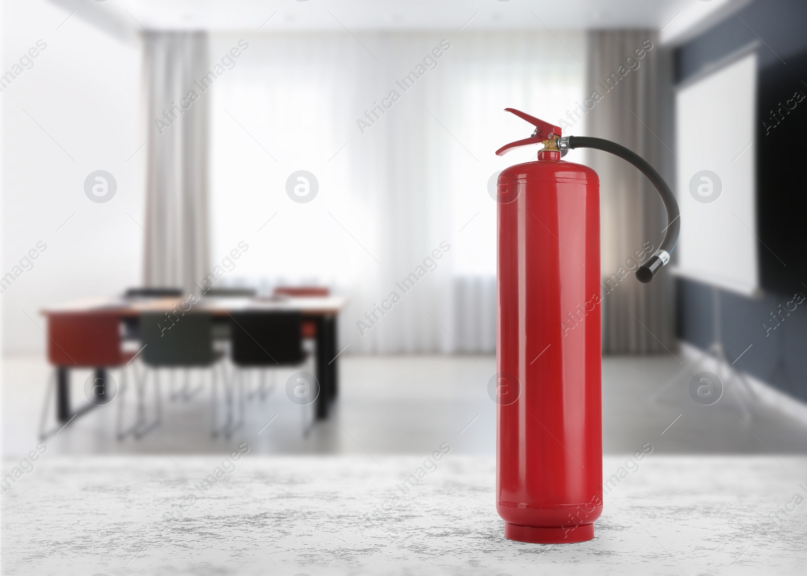 Image of Fire extinguisher on stone table in meeting room. Space for text