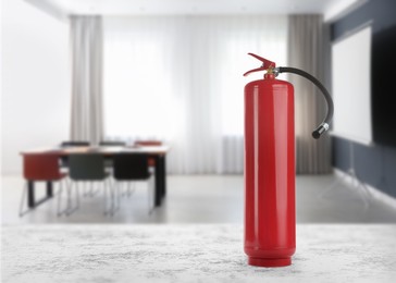 Image of Fire extinguisher on stone table in meeting room. Space for text