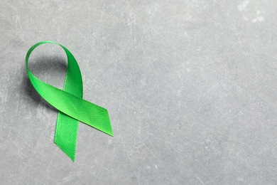 Photo of Green ribbon on grey background. Cancer awareness