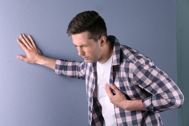 Photo of Young man having heart attack on color background