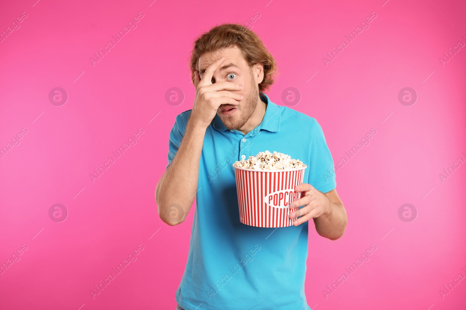 Photo of Emotional man with popcorn during cinema show on color background