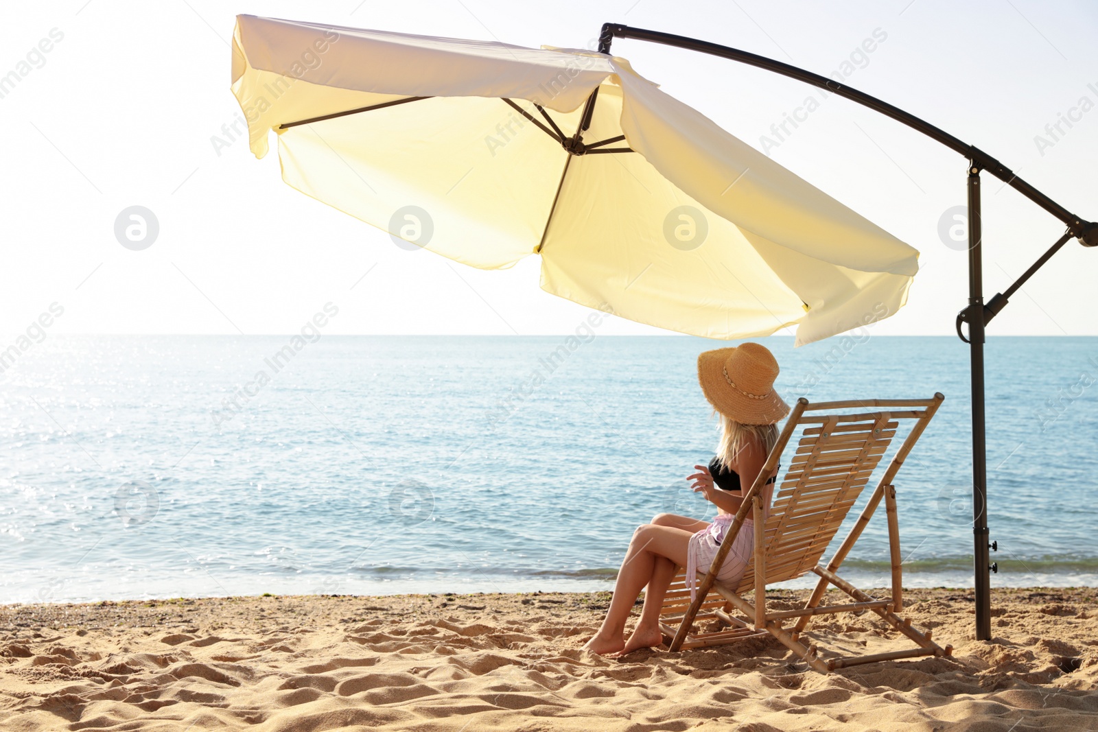 Photo of Woman relaxing on deck chair at sandy beach. Summer vacation