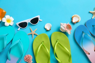 Photo of Flat lay composition with different flip flops on blue background, space for text. Summer beach accessories