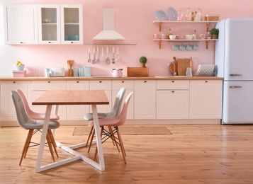 Stylish pink kitchen interior with dining table and chairs