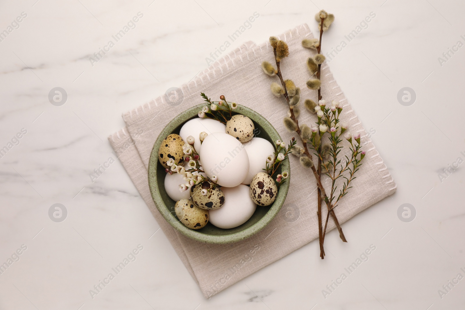 Photo of Easter eggs, flowers and pussy willow branches on white marble table, top view