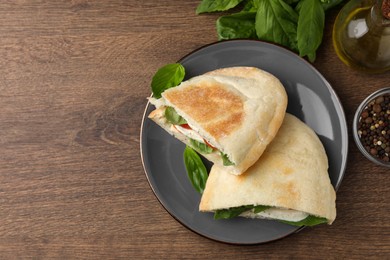 Delicious pita sandwiches with mozzarella, tomatoes and basil on wooden table, flat lay. Space for text
