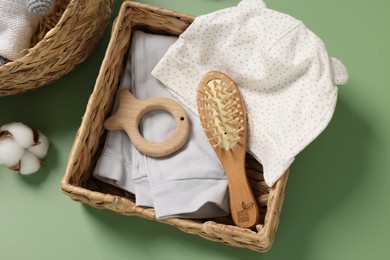 Different baby accessories in wicker boxes on green background