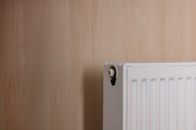 Photo of Modern radiator on wooden wall, space for text. Central heating system