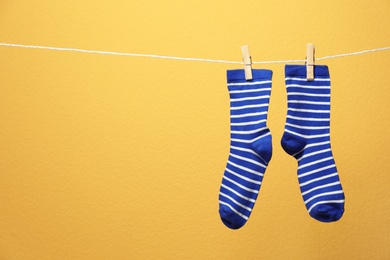 Photo of Cute socks on laundry line against color background. Space for text