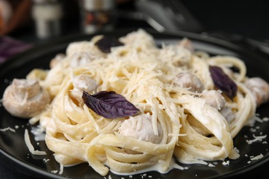 Delicious pasta with mushrooms on black plate, closeup