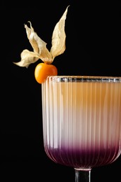 Photo of Tasty cocktail decorated with physalis fruit on black background, closeup