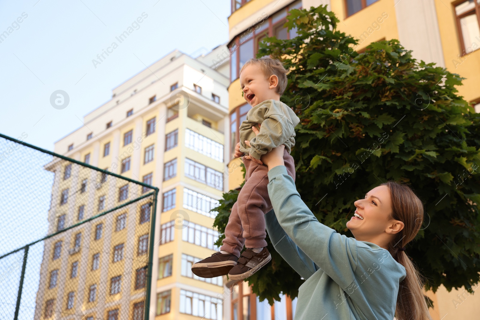 Photo of Happy nanny with cute little boy having fun outdoors, space for text