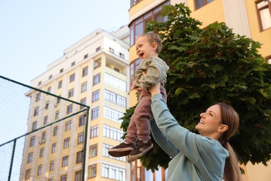 Happy nanny with cute little boy having fun outdoors, space for text