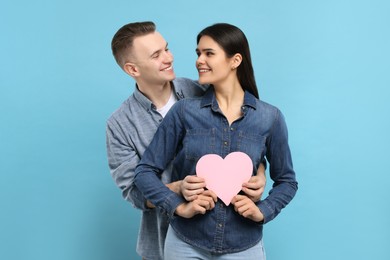 Photo of Lovely couple with decorative heart on light blue background. Valentine's day celebration