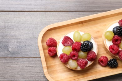 Photo of Delicious tartlets with berries on wooden table, top view