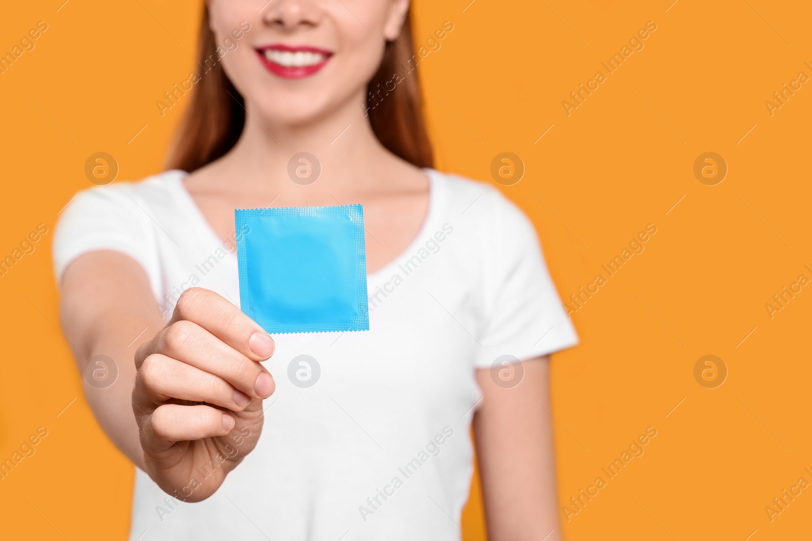 Photo of Woman holding condom on yellow background, closeup and space for text. Safe sex