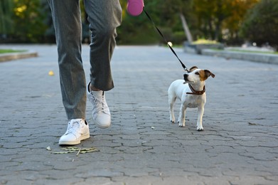 Photo of Man with adorable Jack Russell Terrier on city street, closeup. Dog walking