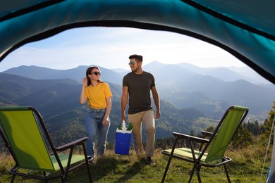 Photo of Couple and cool box with bottles of beer in mountains, view from tent