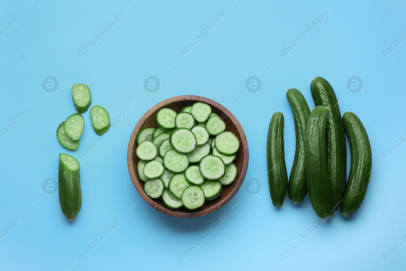 Photo of Fresh ripe cucumbers on light blue background, flat lay