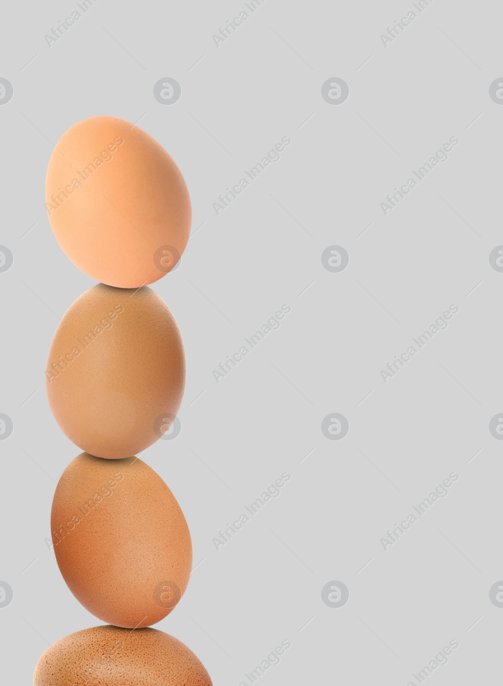 Image of Stacked fresh chicken eggs against light grey background. Space for text