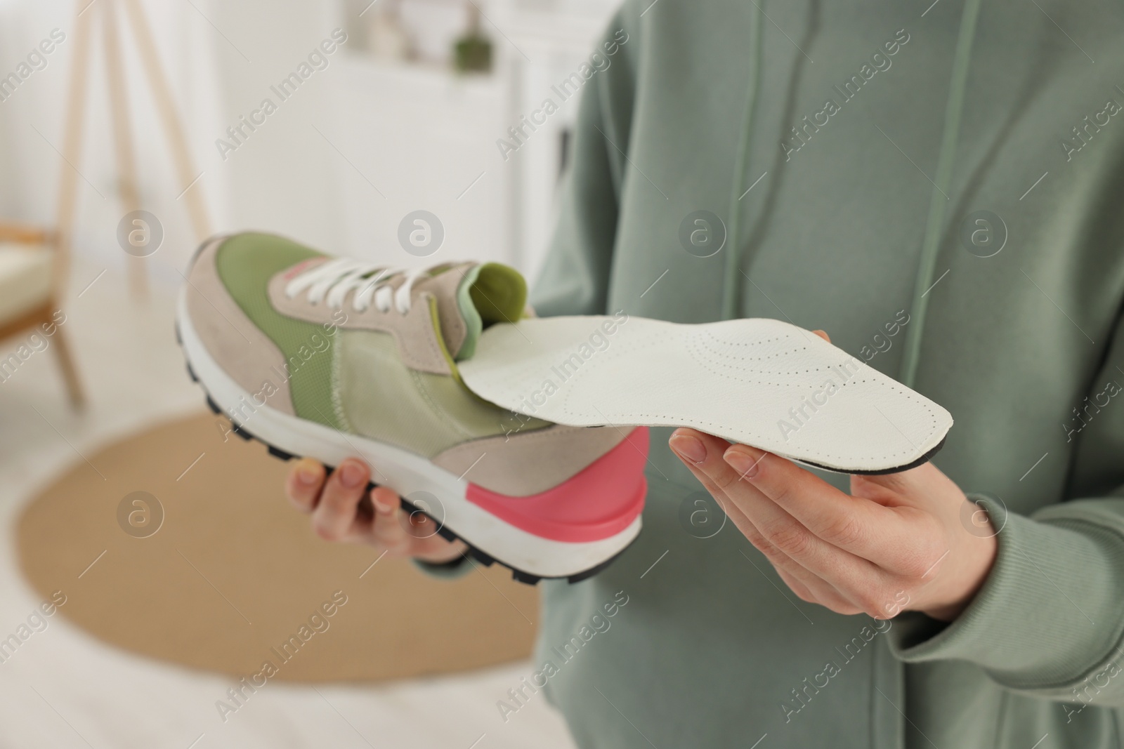 Photo of Woman putting orthopedic insole into shoe at home, closeup. Foot care