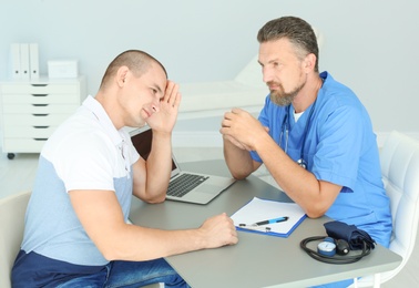Male medical assistant consulting patient in clinic